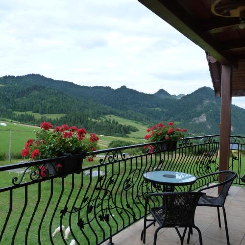 a balcony with a table and chairs and flowers at Agroturystyka Pod Zamczyskiem in Sromowce Wyżne