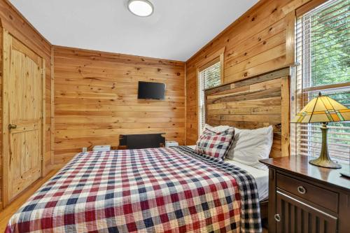 a bedroom with a bed in a room with wooden walls at New Mtn Views Hot Tub Arcade Chess in Sautee Nacoochee