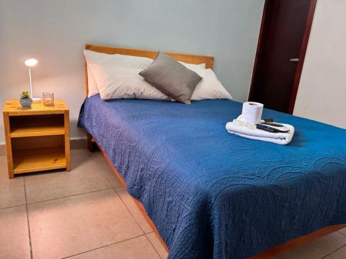 a bed with a blue blanket and a night stand at Hotel Azahara in Cancún