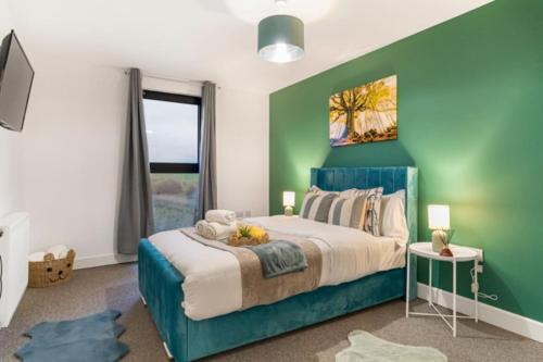 a bedroom with a large bed with a green wall at Affordable 1 & 2 Bed Apartments in Slough, Great Heathrow Location in Colnbrook