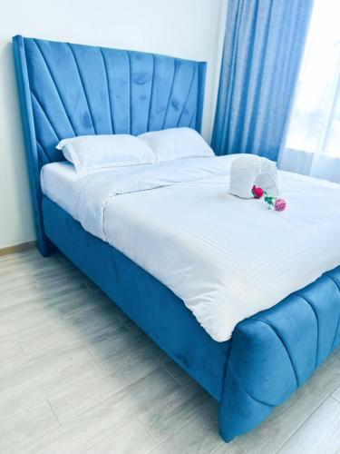 a blue bed with a blue headboard and flowers on it at Urban Stays-Two bedroom Near JKIA Airport in Nairobi