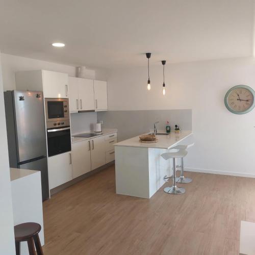 a kitchen with white cabinets and a clock on the wall at Paradise Point Sea & Mountain view in Estreito da Calheta
