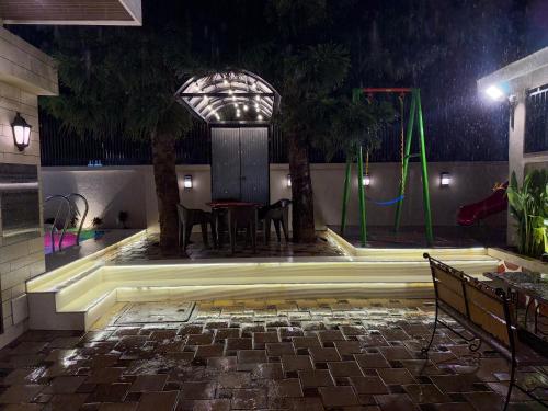 a pool with a table and a playground at night at Zaid & Nida House in Panchgani