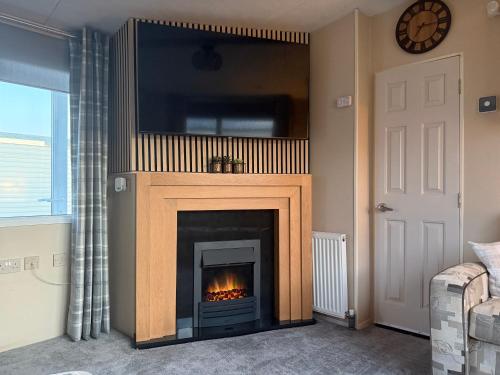 a living room with a fireplace with a tv above it at Caravan by the sea in Gristhorpe