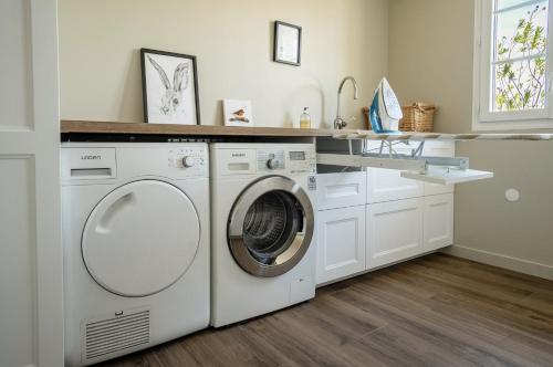 a white laundry room with a washer and dryer at Proche Puy duFou - Les Buardieres in Saint-Pierre-des-Échaubrognes