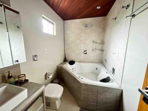 a bathroom with a tub and a toilet and a sink at 250m do Mar com Hidromassagem, Chale aconchegante para relaxar in Governador Celso Ramos
