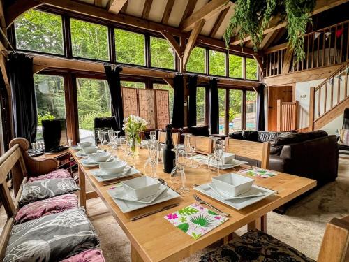 a long wooden table in a room with windows at Nightingale Barn - Stunning & Huge in Etchingham