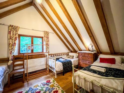 a attic room with two beds and a window at Nightingale Barn - Stunning & Huge in Etchingham