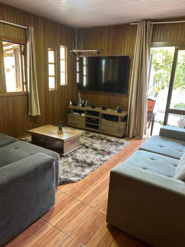 ein Wohnzimmer mit zwei Sofas und einem Flachbildfernseher in der Unterkunft Chalé cipreste 3 Quartos in Gramado