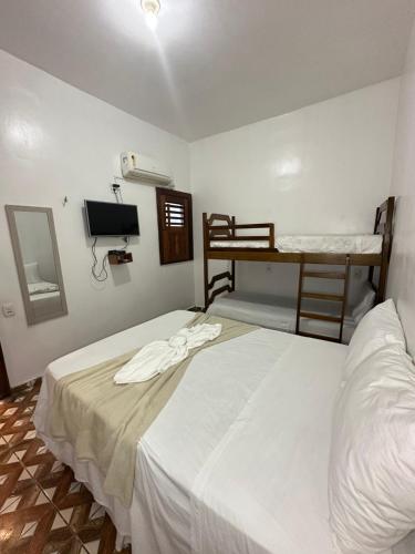 a bedroom with two bunk beds and a television at Morada da Praia Pousada in Jericoacoara