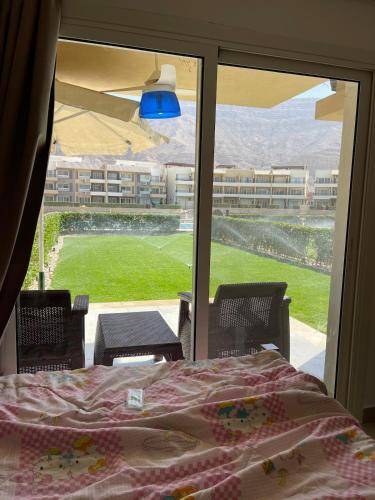 a bedroom with a bed and a view of a yard at Ground peaceful chalet 3 bedroom with 6 king bed & 2 bathrooms &private garden marvelous land escape Murano resort Ain sokhna in Ain Sokhna