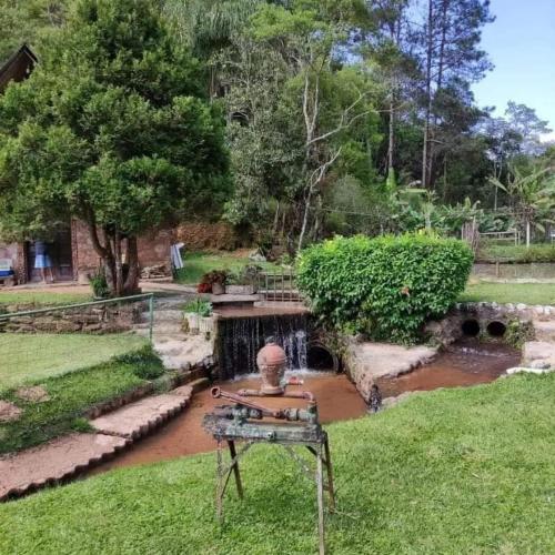 a garden with a statue in the grass at Sítio Isolina Piscina, Campo e Lago in Juquitiba