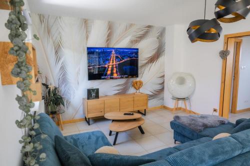 a living room with a blue couch and a tv at Gite des cigognes in Kintzheim