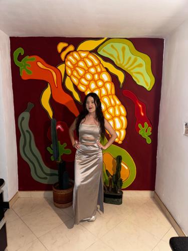 a woman standing in front of a wall with a painting at Hostal Galería de la Montaña, Medellin in Estación El Salto