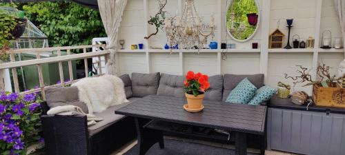 a patio with a couch and a table with flowers on it at Øya husrom-enkeltsenger-kjøkken-bad in Sarpsborg