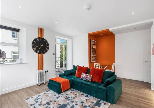 a living room with a green couch and a clock at The Lanes Sunset Terrace in Brighton & Hove