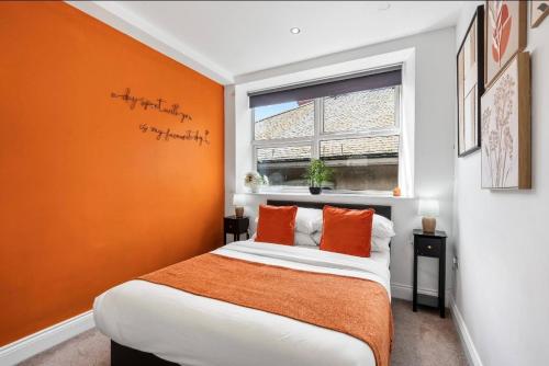 a bedroom with a bed with an orange wall at The Lanes Sunset Terrace in Brighton & Hove