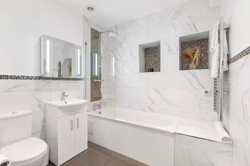 a white bathroom with a tub and a toilet and a sink at The Lanes Sunset Terrace in Brighton & Hove