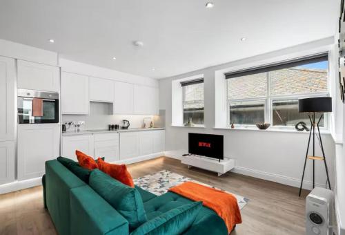 a living room with a green couch and a kitchen at The Lanes Sunset Terrace in Brighton & Hove