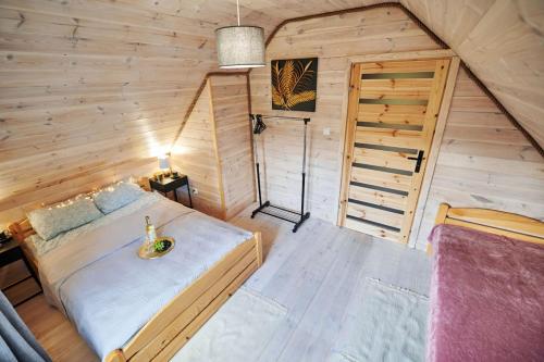 Un dormitorio con una cama en una cabaña de madera. en Leśne Klimaty, en Marózek