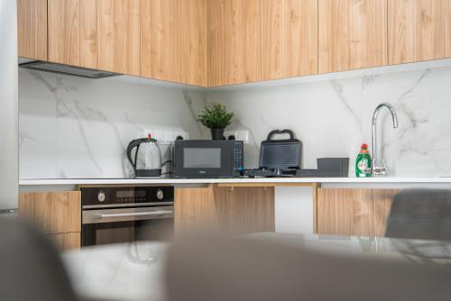 a kitchen with wooden cabinets and a counter top at Serene Gardens 2BR Stylish Apartment with Pool and Gym in Livadhia