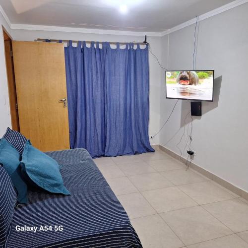 a living room with a bed and a tv at CASA - 2 minutos do aeroporto - 3 qtos com ar in Campo Grande