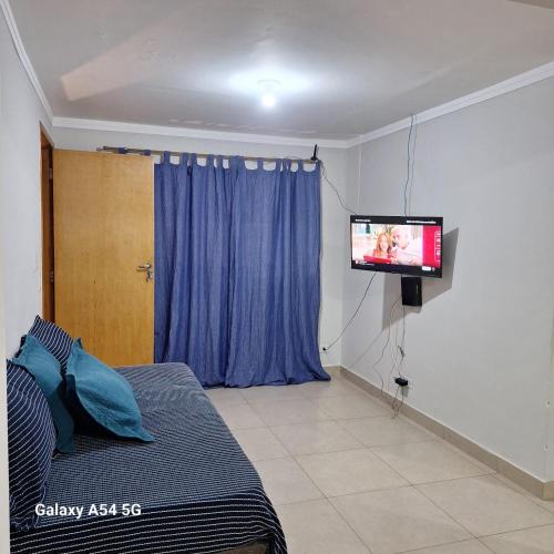 a bedroom with a bed and a tv on the wall at CASA - 2 minutos do aeroporto - 3 qtos com ar in Campo Grande