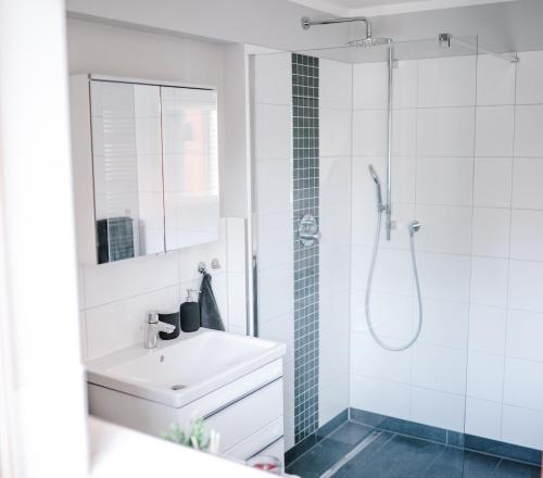 a white bathroom with a sink and a shower at Panorama-Seeblick, Privater Steg, Balkon, Parkplatz in Plön