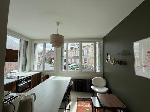 a kitchen with a table and chairs and windows at Veules-les-Roses Studio in Veules-les-Roses