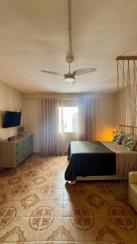 ein Schlafzimmer mit einem Bett und einem Deckenventilator in der Unterkunft Vista Mar - Kitnet Espaçosa - Tupi in Praia Grande