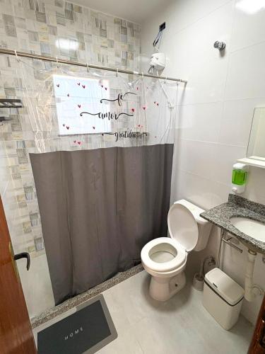 a bathroom with a shower curtain and a toilet at Oasis das Dunas in Cabo Frio