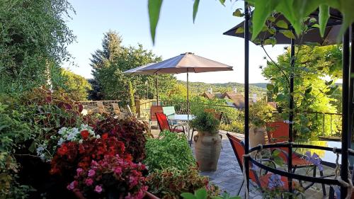 a patio with a table with an umbrella and flowers at T.H.NY Village Inn Cottage in Tihany