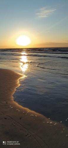 a sunset on a beach with the ocean at Apartament przy Lesie - Domki u Piotrusia in Żarnowska