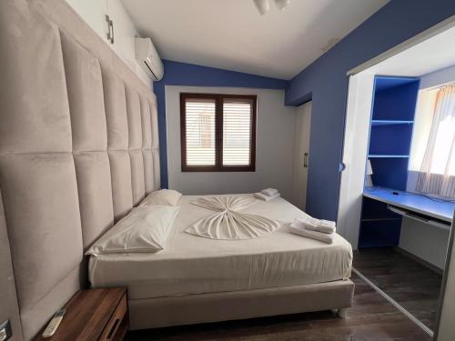 a bedroom with a white bed with a blue wall at Vila Behar - Penthouse Apartment in Sarandë