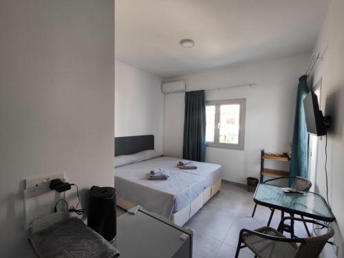 a bedroom with a bed and a table and a window at Golden Sun Rooms - Adults Only in Ayia Napa