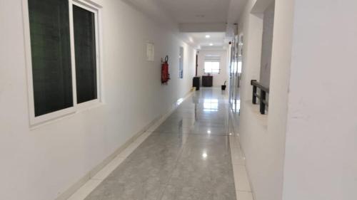 a hallway with white walls and white floors and a window at The Zenith Stay in Hyderabad