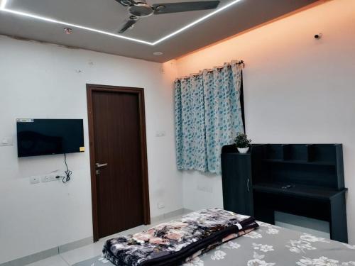 a room with a bed and a television and a door at The Zenith Stay in Hyderabad