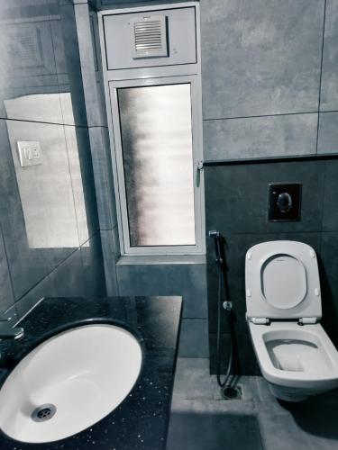 a bathroom with a toilet and a sink and a window at The Zenith Stay in Hyderabad