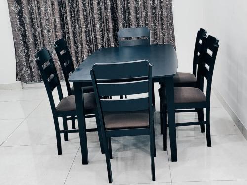 a black dining room table with four chairs at The Zenith Stay in Hyderabad