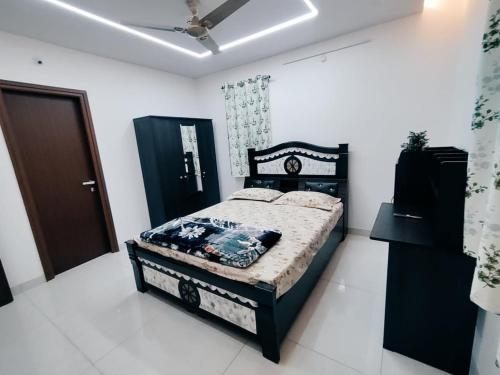 a bedroom with a black bed in a white room at The Zenith Stay in Hyderabad