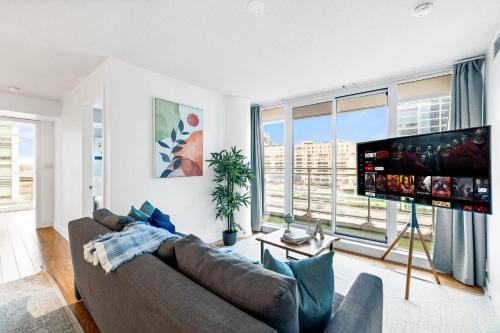 a living room with a couch and a flat screen tv at Spacious 3BR Condo w Patio & Skyline Views in Toronto