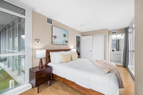 a bedroom with a white bed and a large window at Spacious 3BR Condo w Patio & Skyline Views in Toronto
