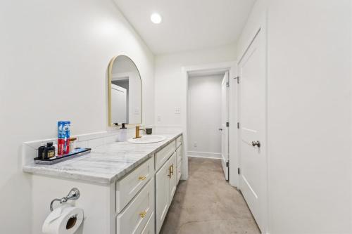 a white bathroom with a sink and a mirror at The Cajun Shack King Bed Cajun Luxury in Lafayette
