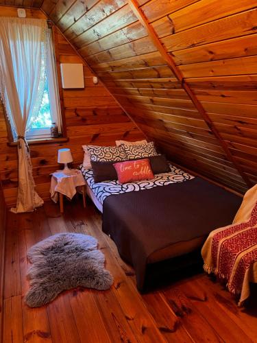 ein Schlafzimmer mit einem Bett in einer Blockhütte in der Unterkunft Domek Nowy Lubiel in Lubiel Stary