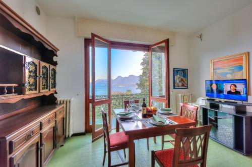 ein Esszimmer mit einem Tisch und einem großen Fenster in der Unterkunft La Finestra Sul Lago - Happy Rentals in Stresa