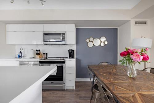 a kitchen with a wooden table with a vase of roses at Spacious 3BR Condo w Patio & City Views in Toronto