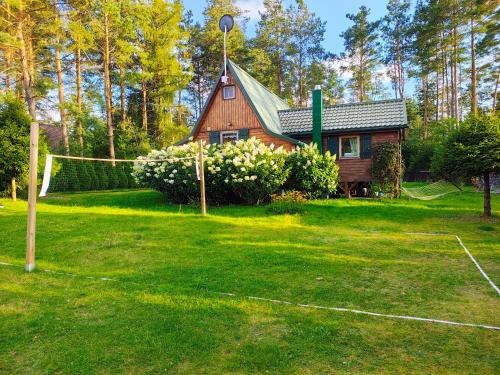 a house with a tennis court in the yard at Chatka Baby Jagi - Domek z balią i kominkiem w lesie pośród jezior in Niesiołowice