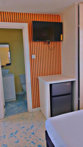 a room with a bathroom with a television on the wall at Oceanview Suites in Saint Georgeʼs