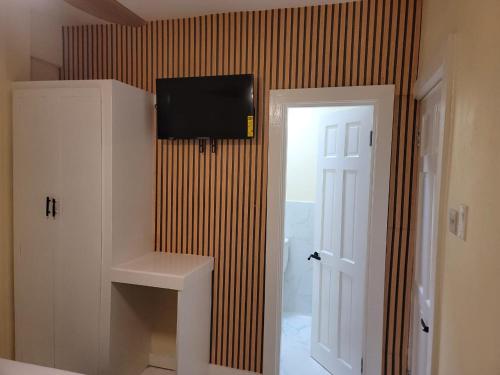 a room with a television on a wall with a door at Oceanview Suites in Saint Georgeʼs