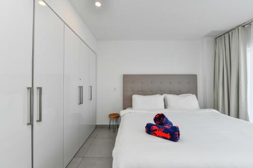a bedroom with a white bed with a red chair on it at Harbour House apt 410 in Oranjestad
